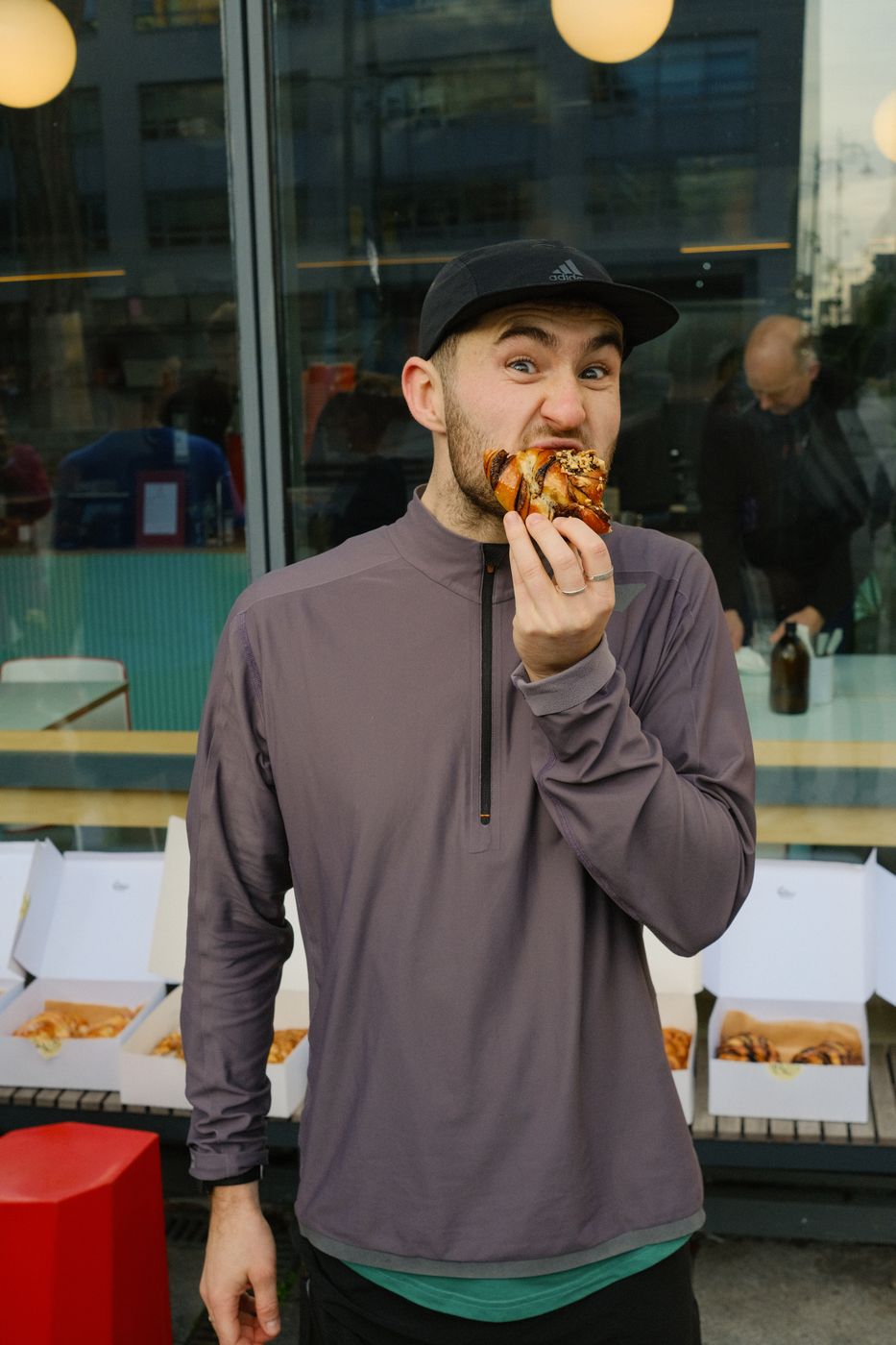 A member in a cap taking a big bite of pizza after the run.